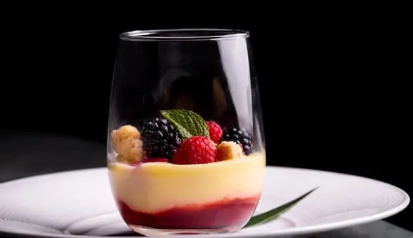 red and white dessert in a glass with berries on top